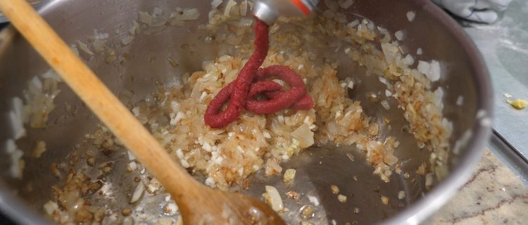 Tomatenmark zu den Zwiebeln geben