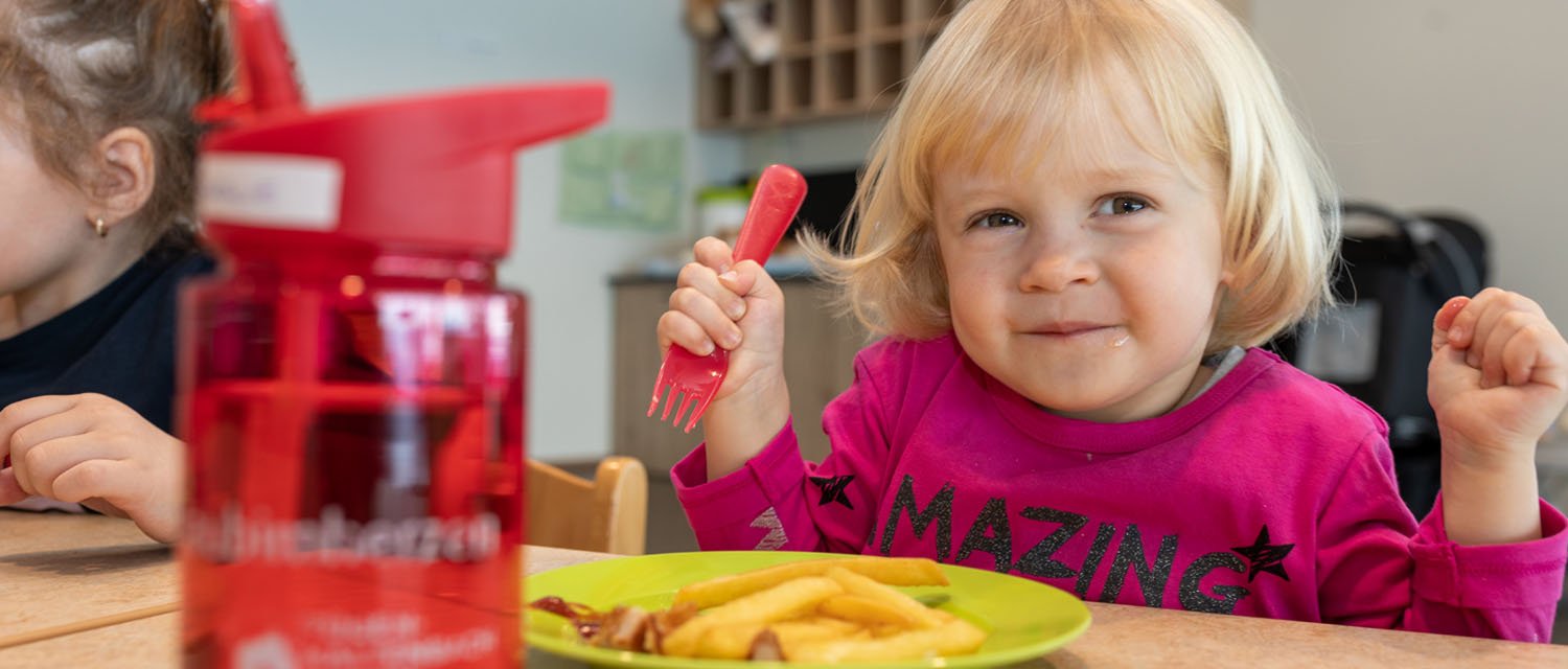 Kind beim Mittagessen im Gästekindergarten 